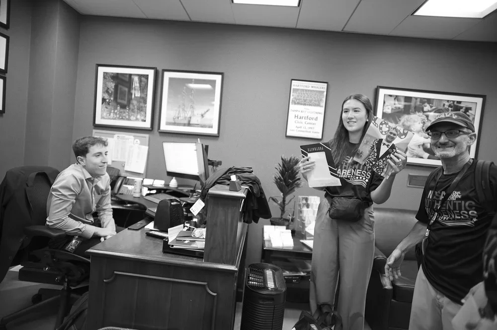 Cristina holds up a portrait of Zack for the office staff.