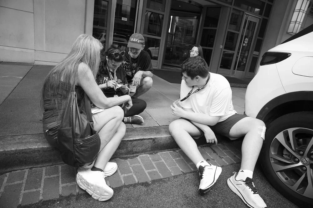 Jadyne stays low on the curb while the others sit down to her level; Luke shows her his badge.