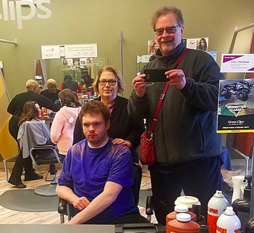  In a recent photo, Ben, seated, gets ready for a haircut while dad David snaps the pic. 