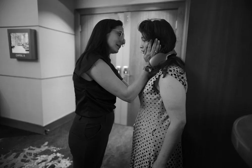 Jackie cups her daughter Jadyne's face in a hallway, helping her steady.