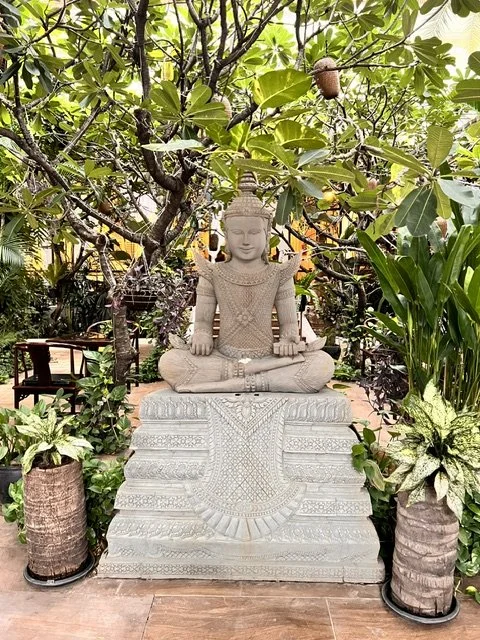 Stone Buddha statue surrounded by lush tropical garden, Cambodia
