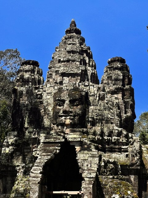 Bayon temple giant stone face tower against brilliant blue sky, Angkor Wat Cambodia