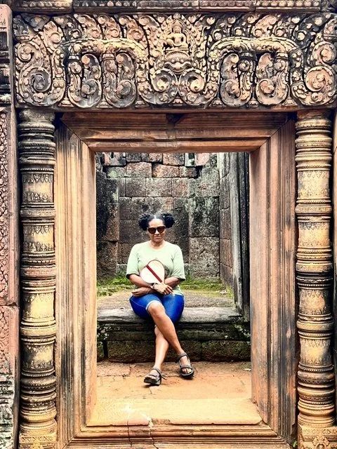 Sondra sitting in ornate carved temple doorway, Cambodia
