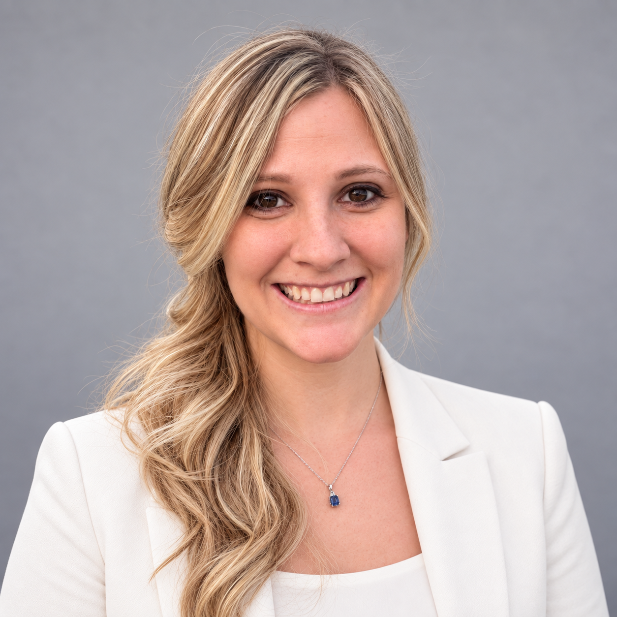 Lindy Culler smiling in a white blazer and light top against a gray background.