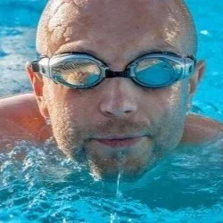 child in goggles rubbing red eyes at poolside