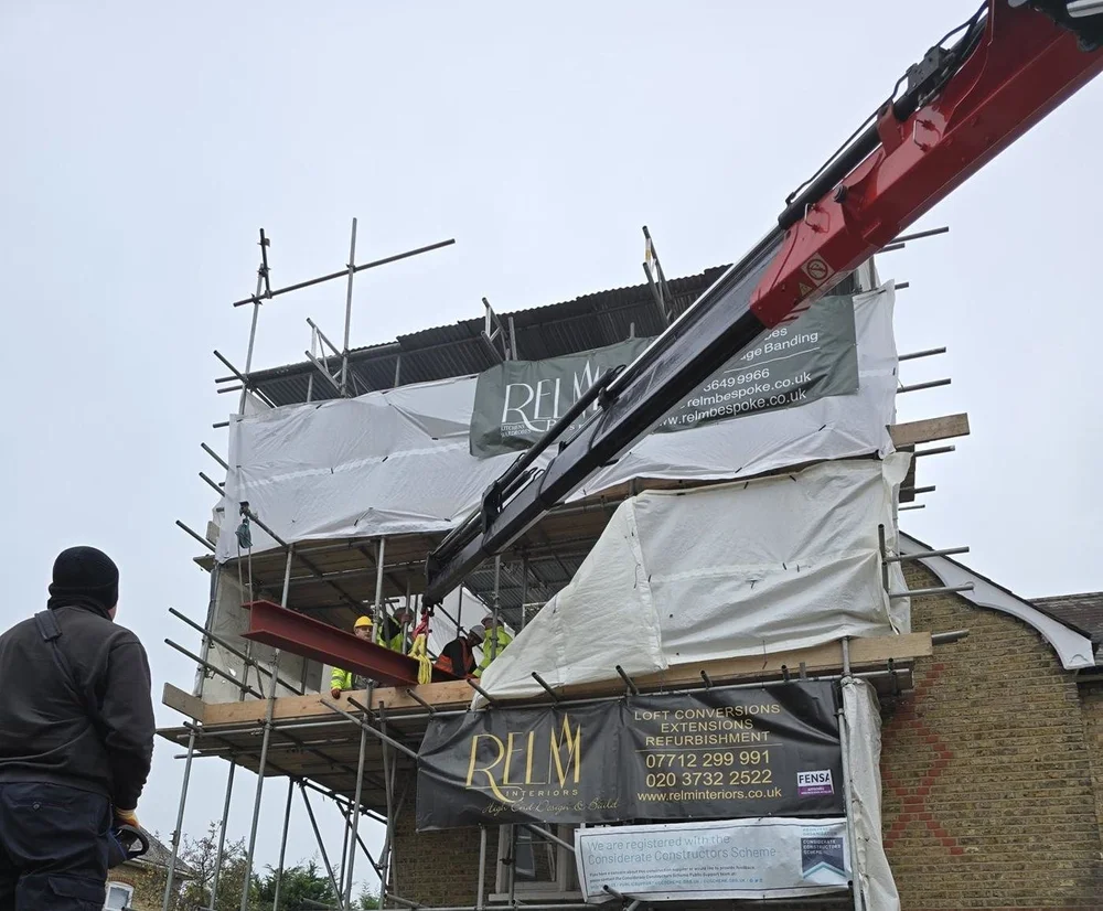 Structural steel beam being craned onto the scaffolding of a Victorian cottage in SW19 during a RELM Interiors renovation