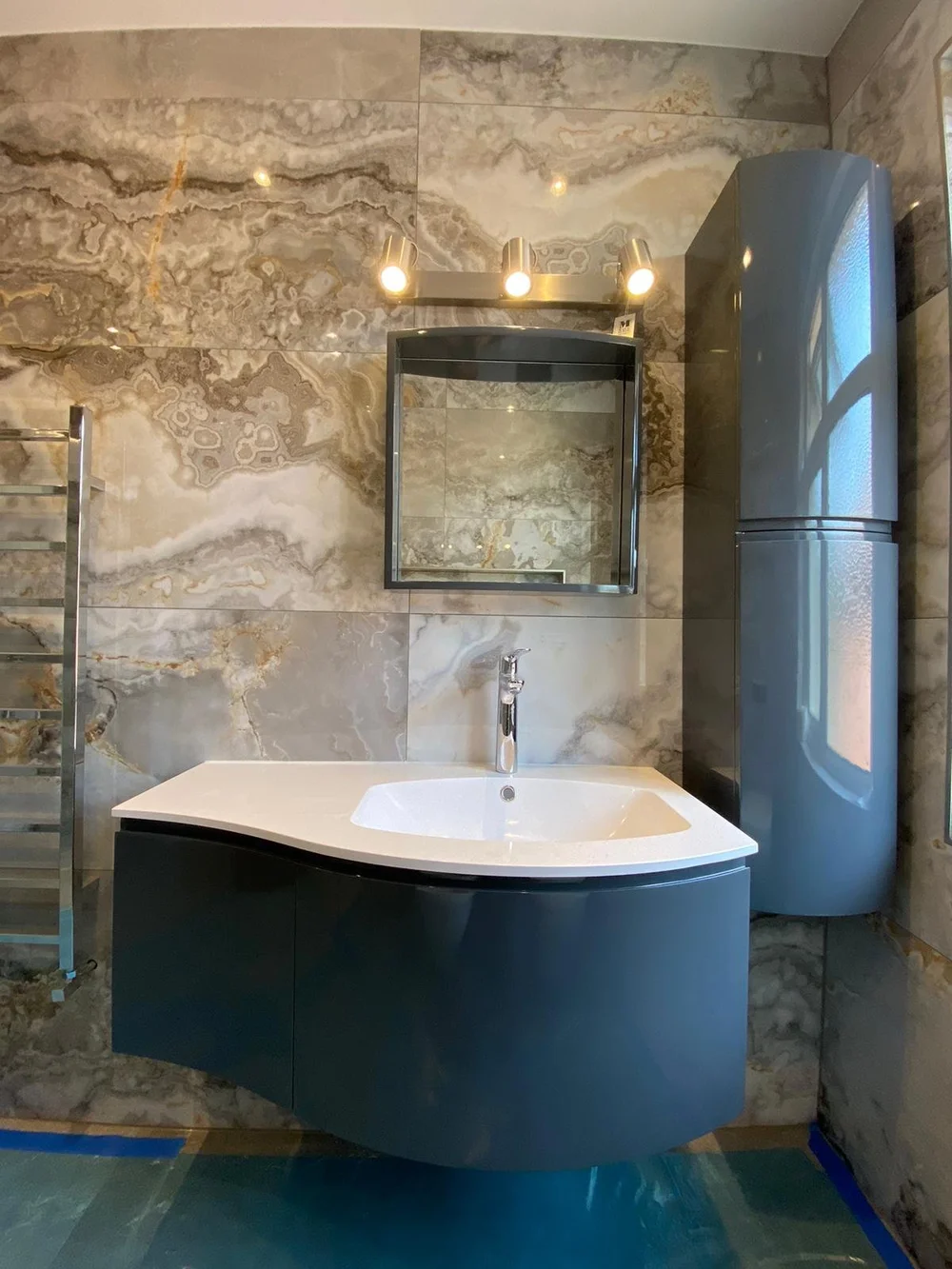 Bathroom with onyx-effect tiles and a curved vanity unit in a Wimbledon house by RELM Interiors