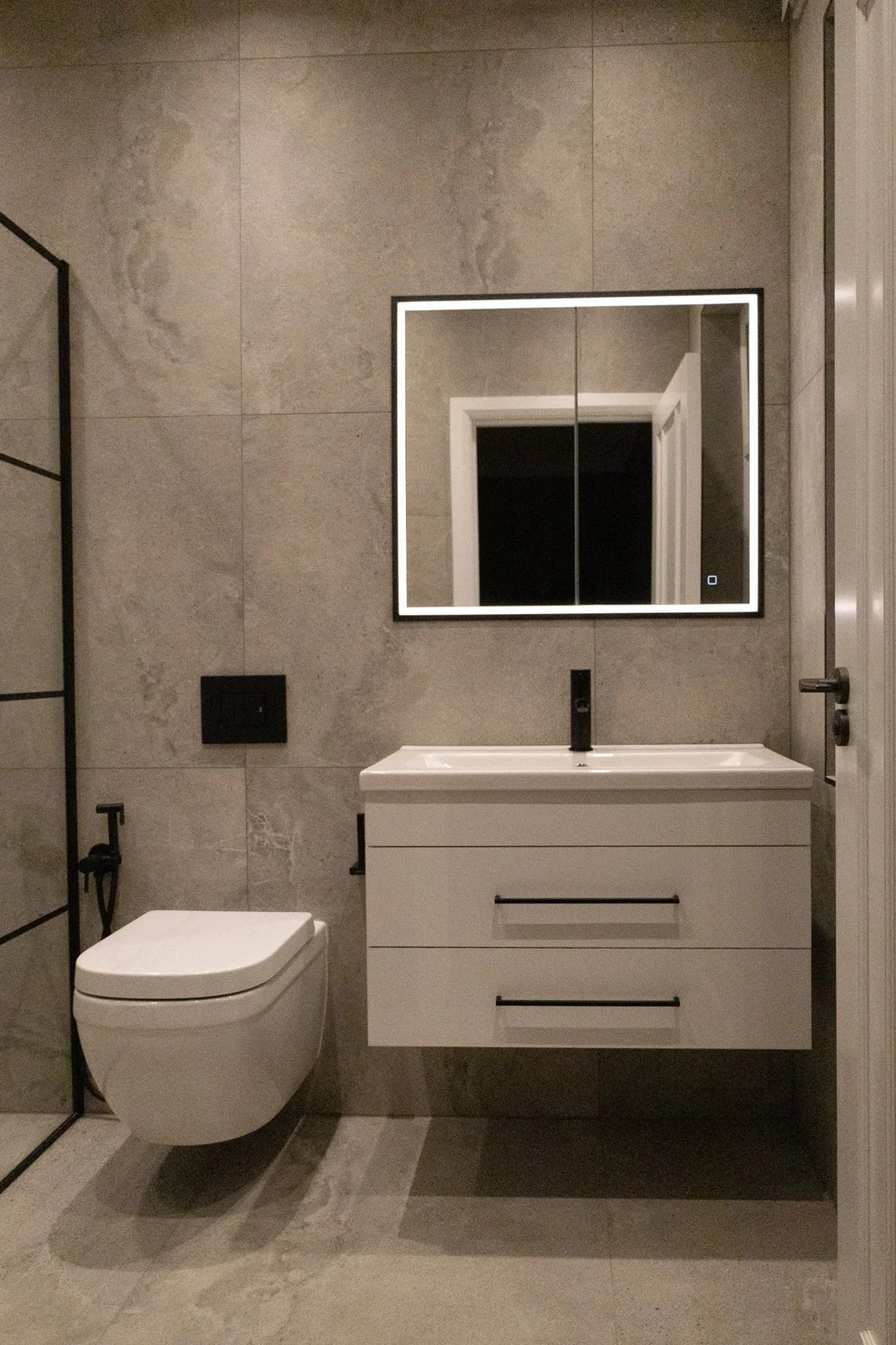 Shower room with stone-effect tiles and black fittings in a Wimbledon house renovation