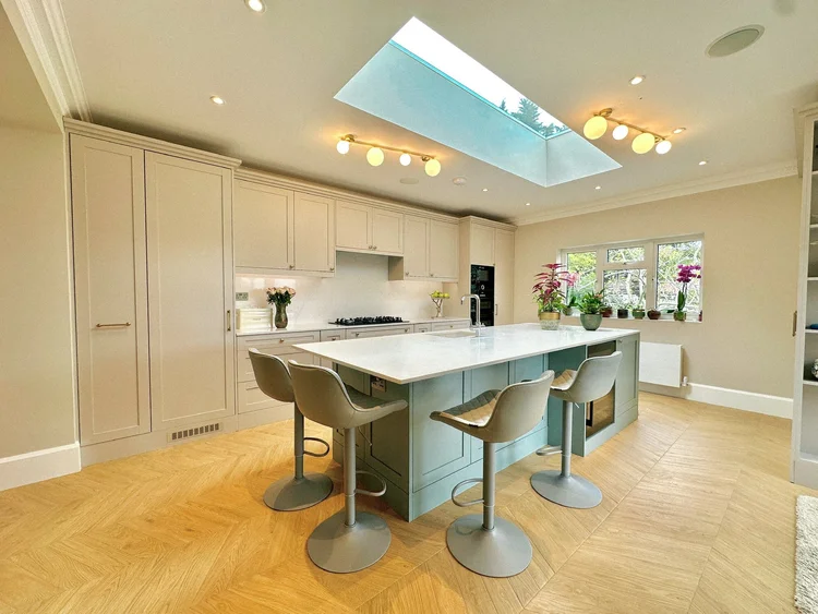 Kitchen with painted units and island under a roof light in a Morden house renovation by RELM Interiors
