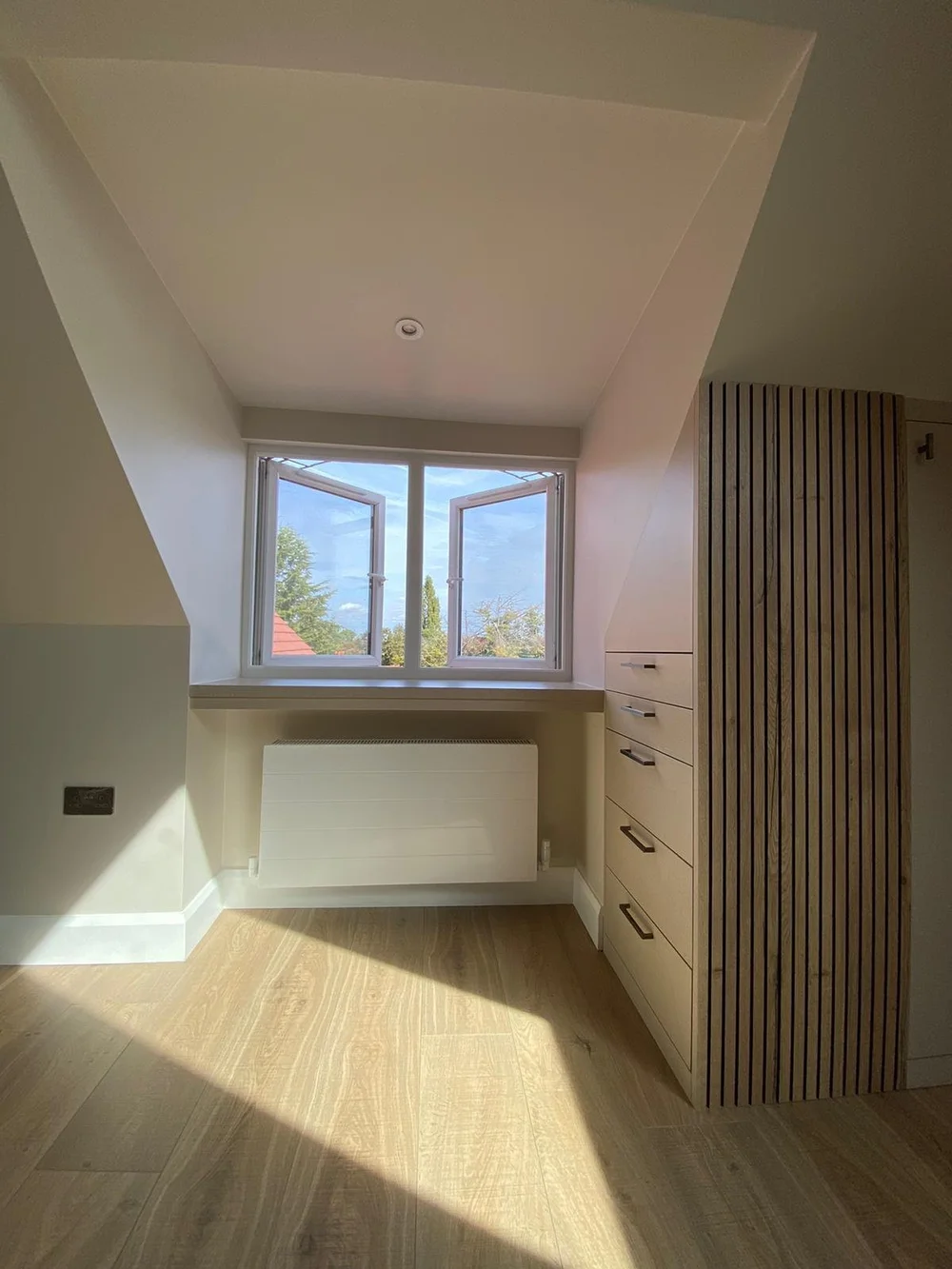 Loft dormer window with built-in drawers and a slatted timber panel in Wimbledon