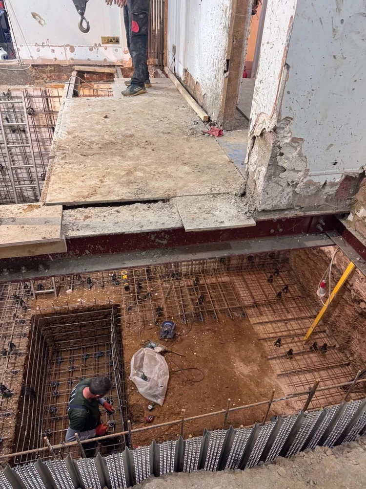 New steel beams supporting the house above a basement excavation, by RELM Interiors