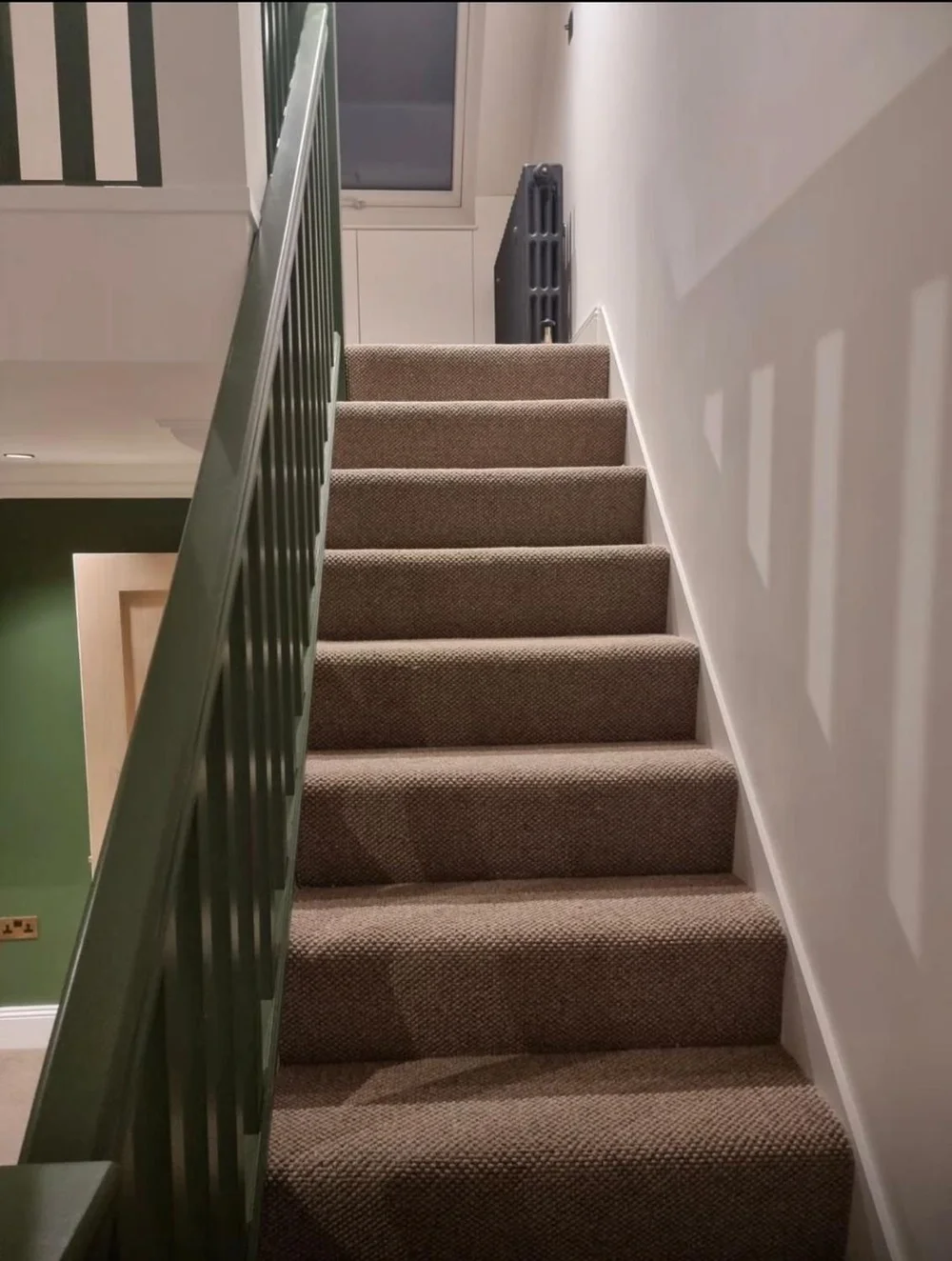 Carpeted staircase with a green balustrade leading to the mezzanine in a Victorian cottage in SW19