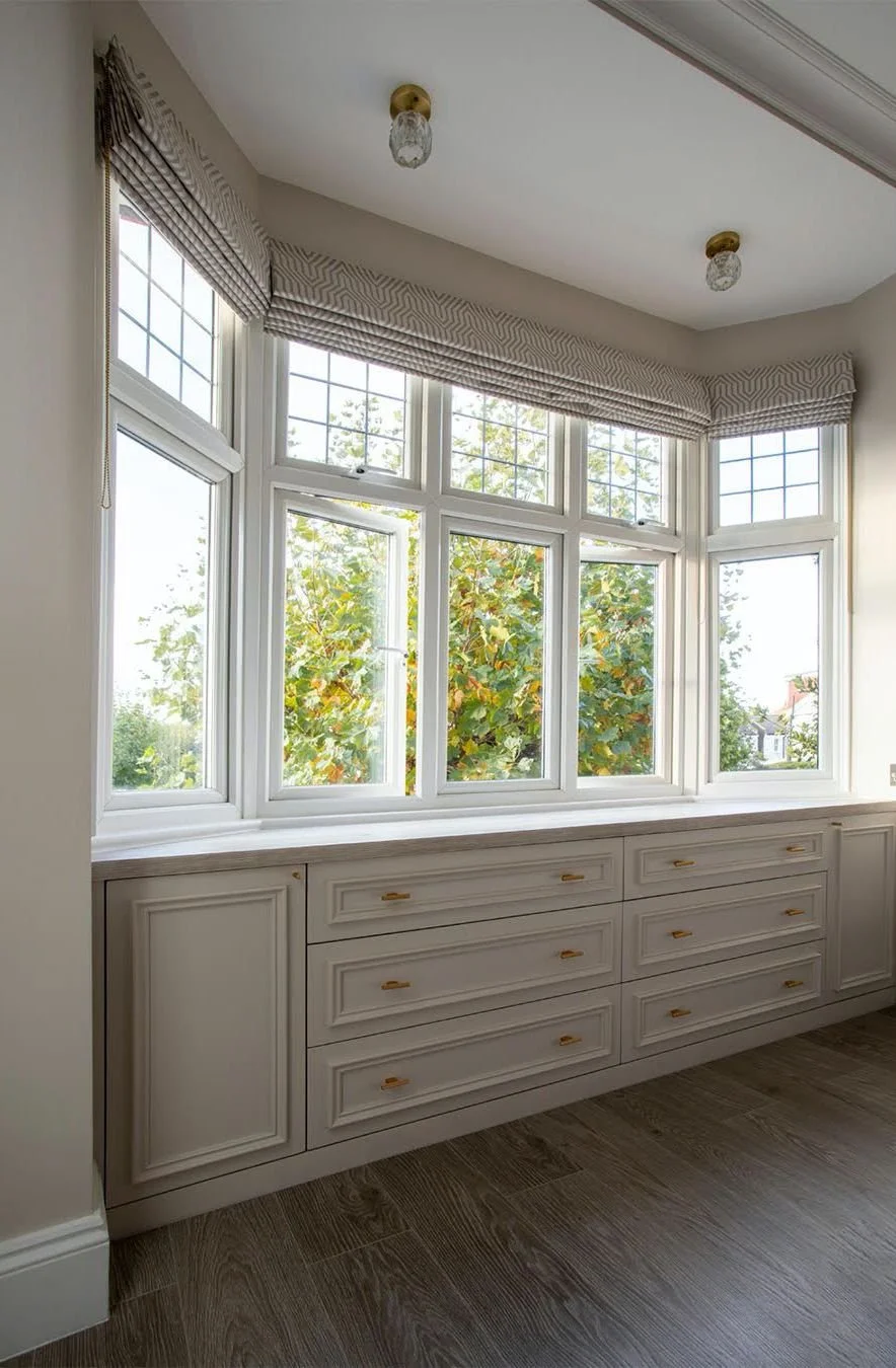 Bright master bedroom with bay window and bespoke window seat in Wimbledon, by RELM Interiors