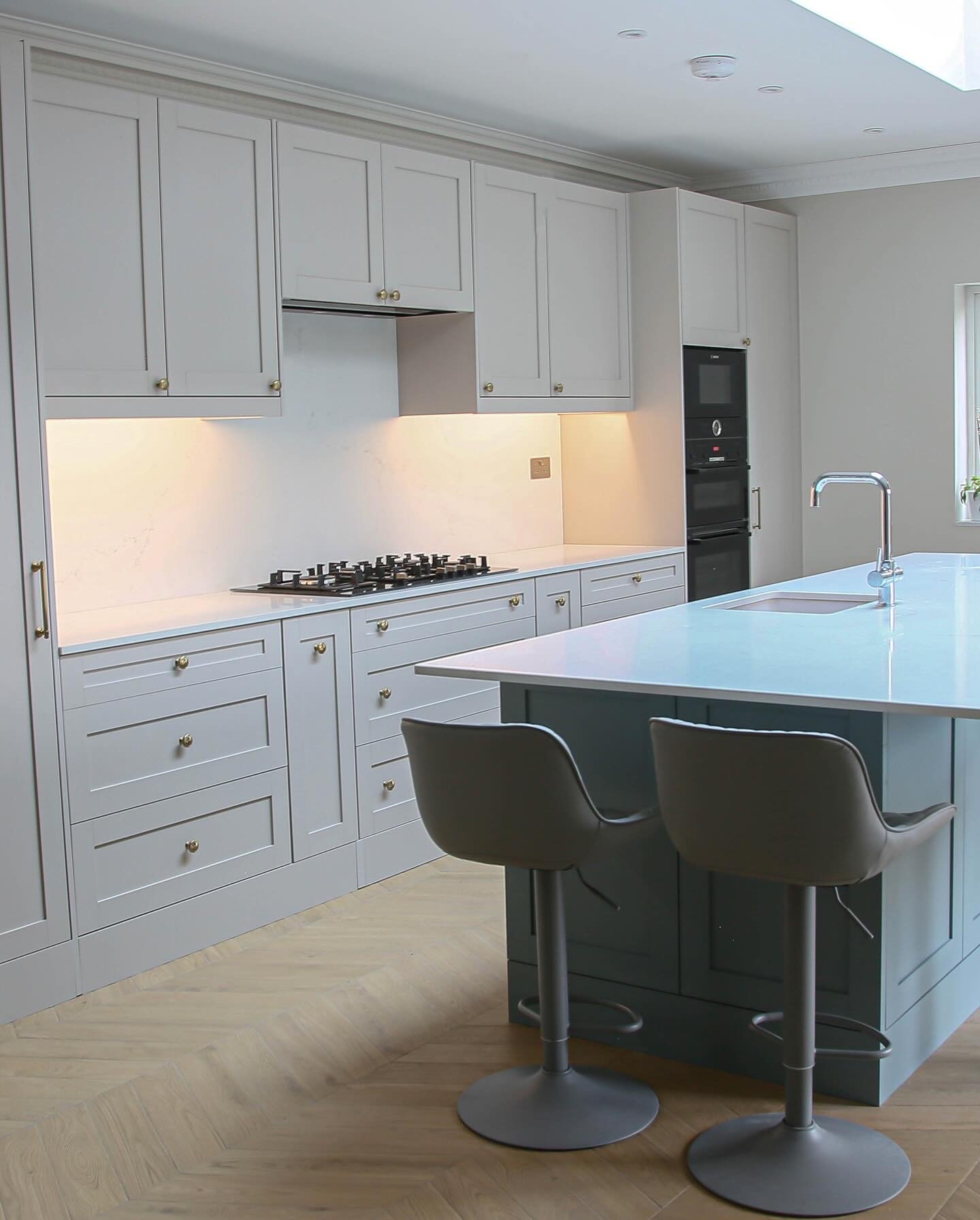 Grey shaker-style kitchen with a contrasting island and herringbone floor in Wimbledon by RELM Interiors