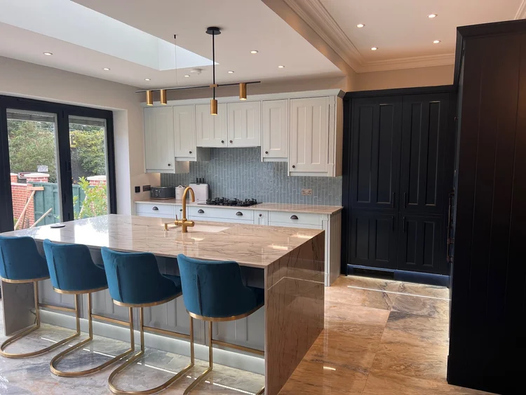 Kitchen with navy tall units and a waterfall-edge island in the rear extension of a 1930s house in Wimbledon
