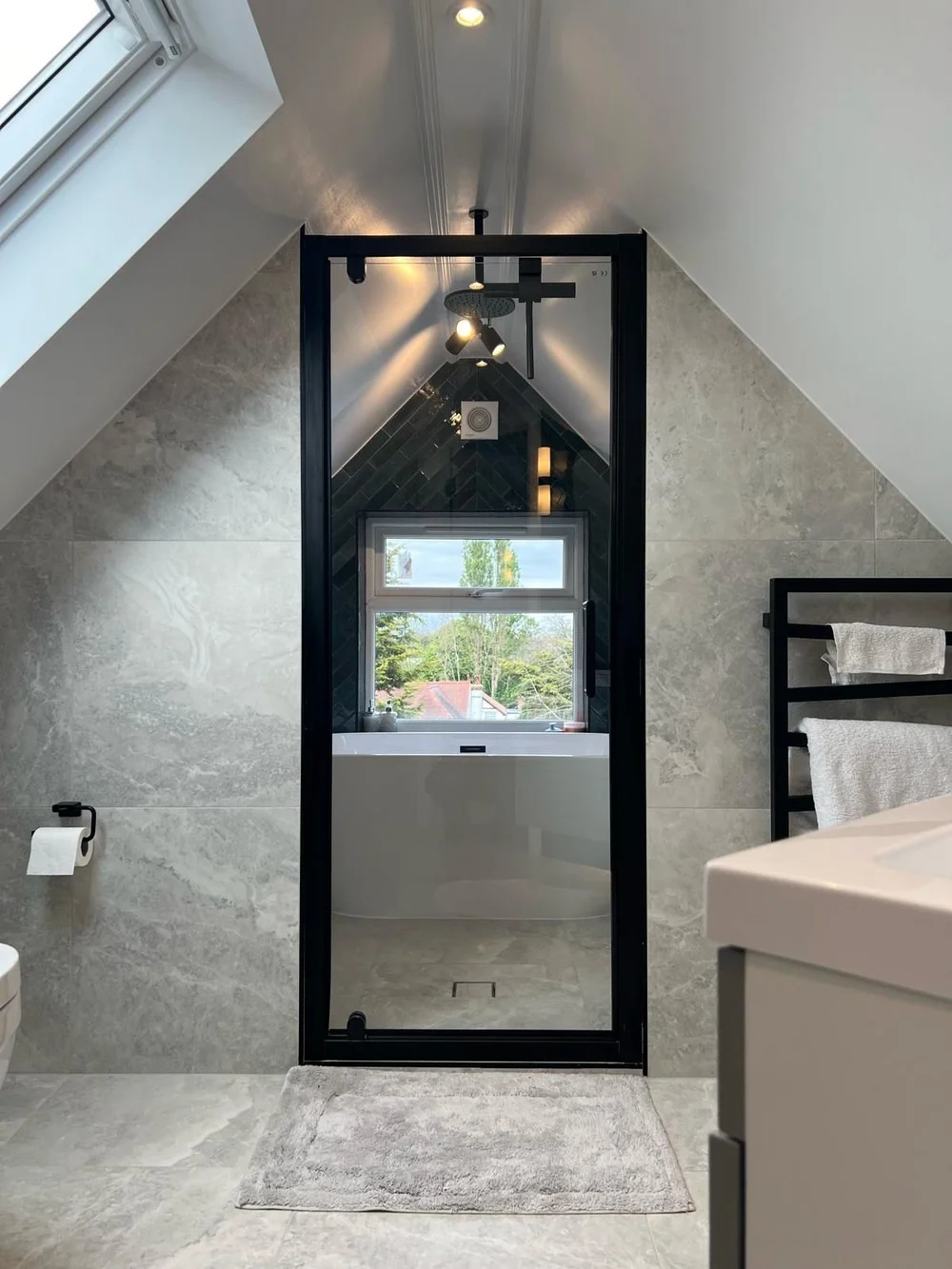 En suite shower room under the roof slope in a Morden loft conversion by RELM Interiors