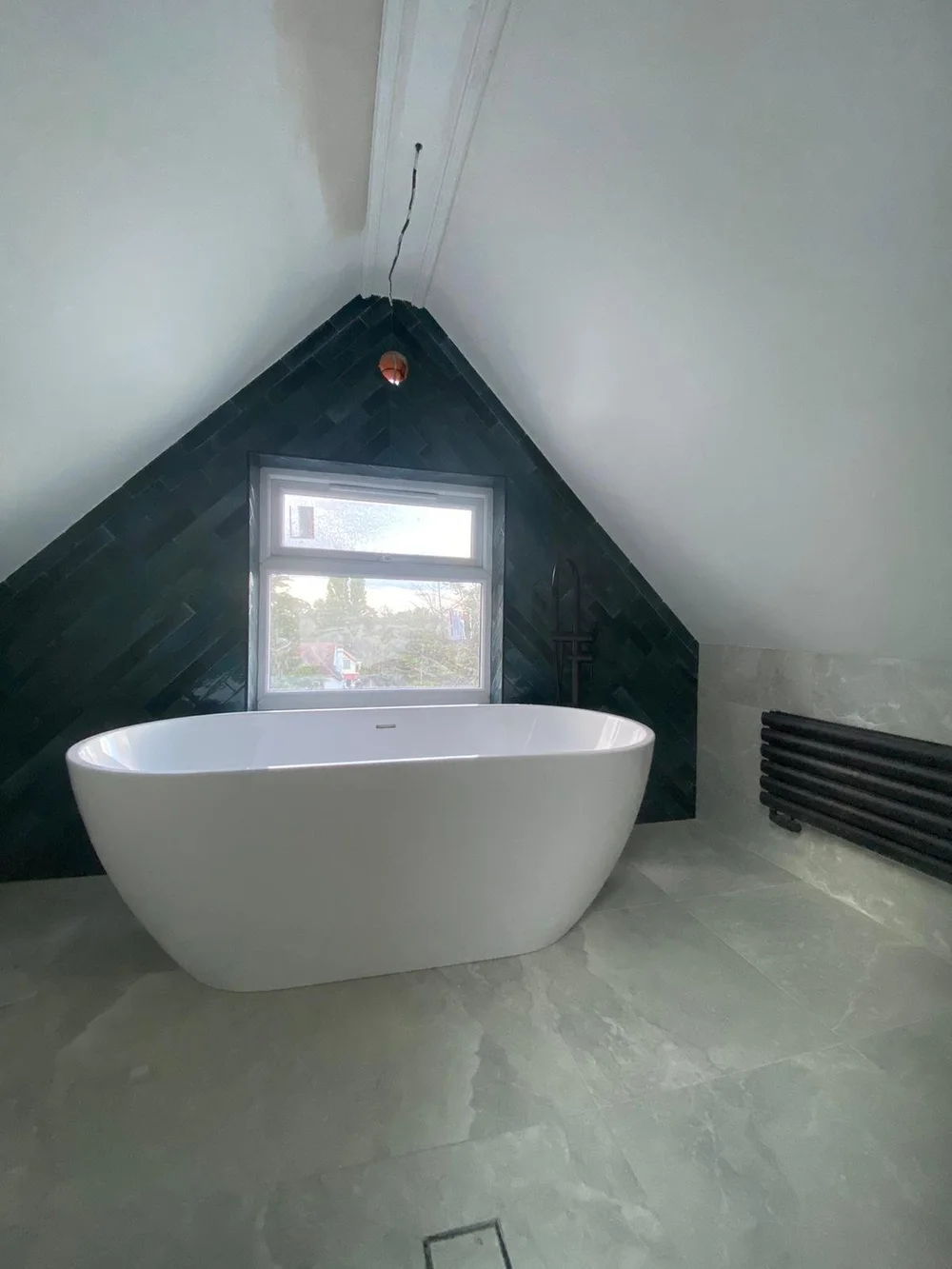 Loft bathroom with a freestanding bath under the gable in Wimbledon