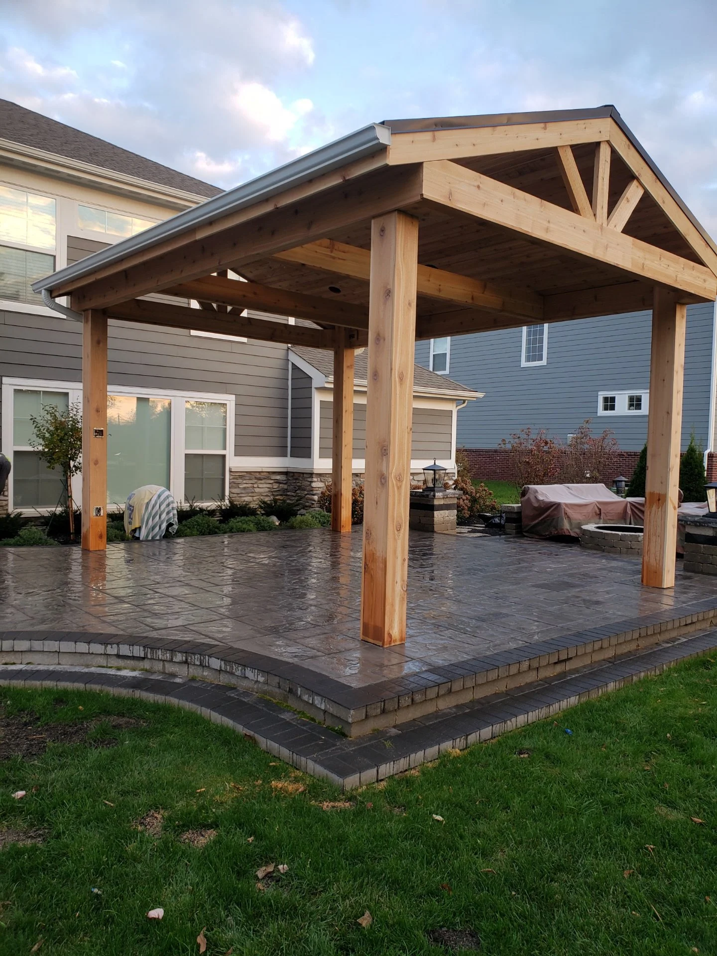 Cedar gable pavilion over stamped concrete patio with paver border