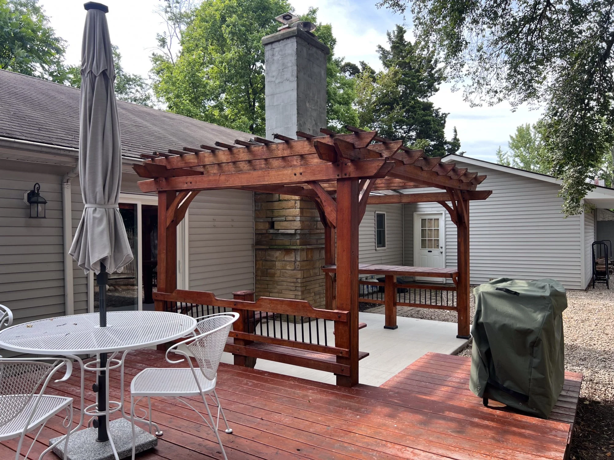 Cedar pergola with stone chimney outdoor fireplace