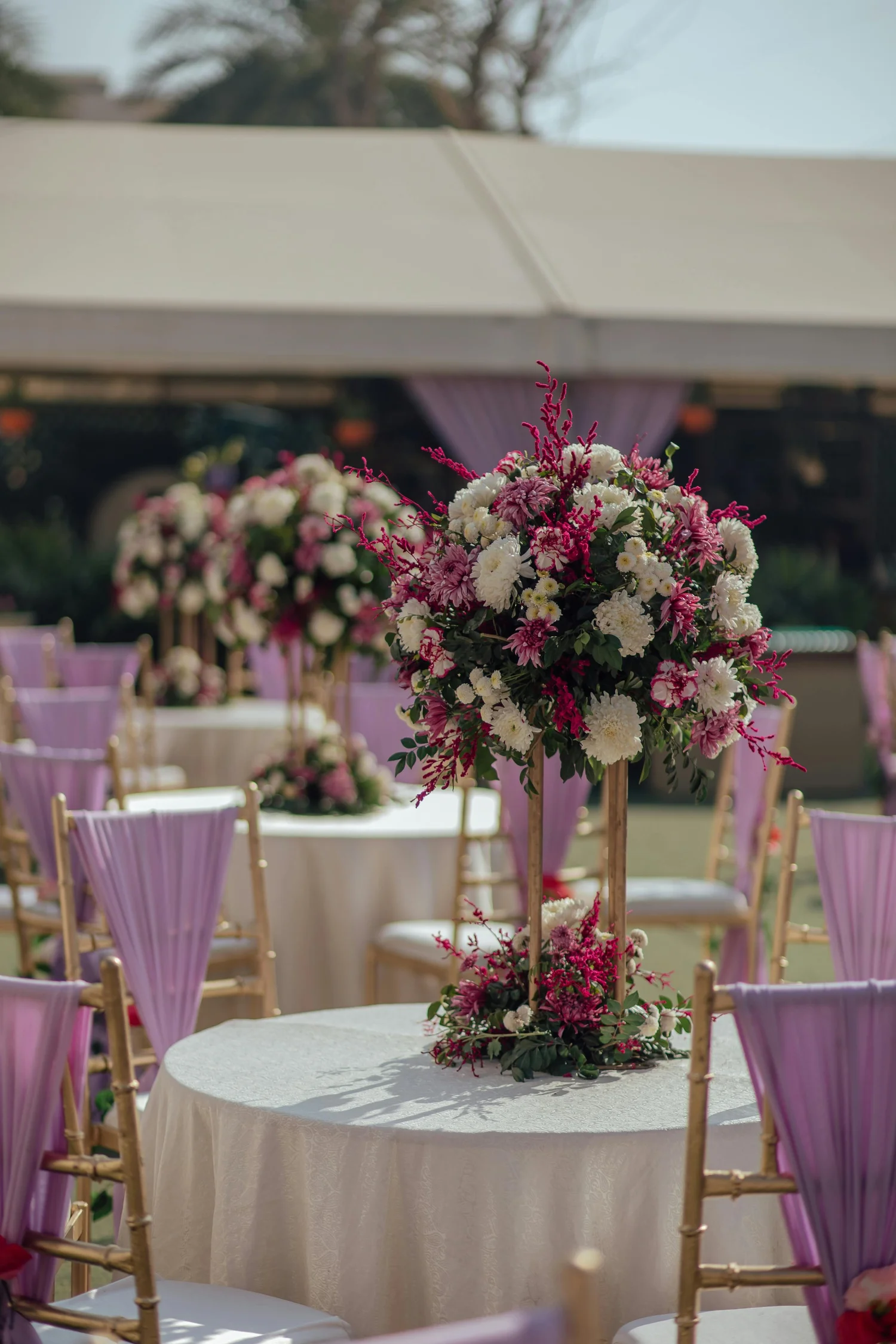 Purple and pink banquet hall with floral centerpieces and gold chairs