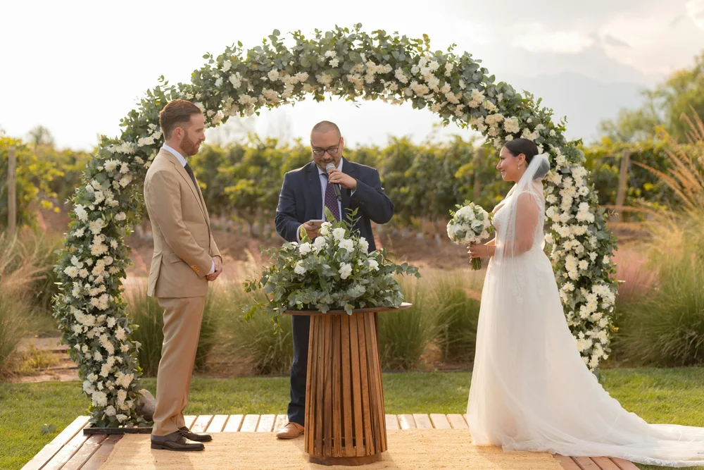 Wedding ceremony outdoors with bride and groom at floral altar