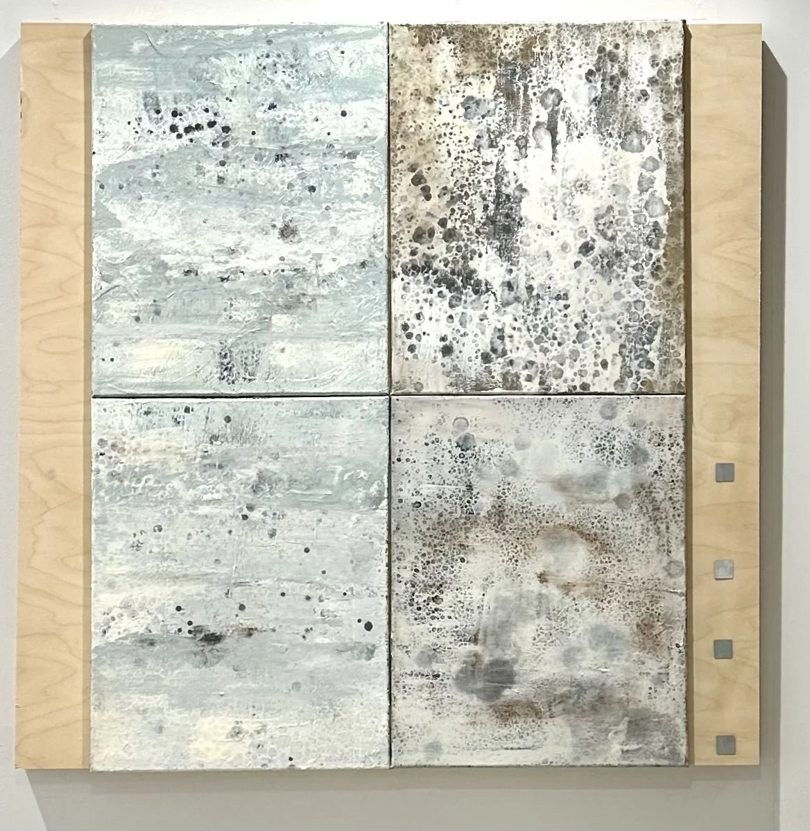 Four pale cellular paintings mounted on wood, with silver NFC tags along the right edge, shown at Creative Portland.
