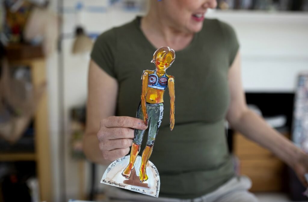 Erin McGee Ferrell holds a painted Ms. Mastectomy paper doll in her studio.