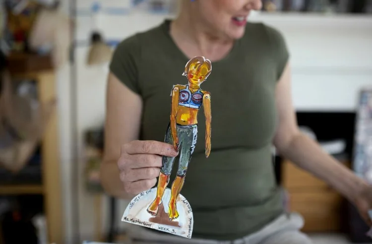 Erin McGee Ferrell holds a painted Ms. Mastectomy paper doll in her studio.
