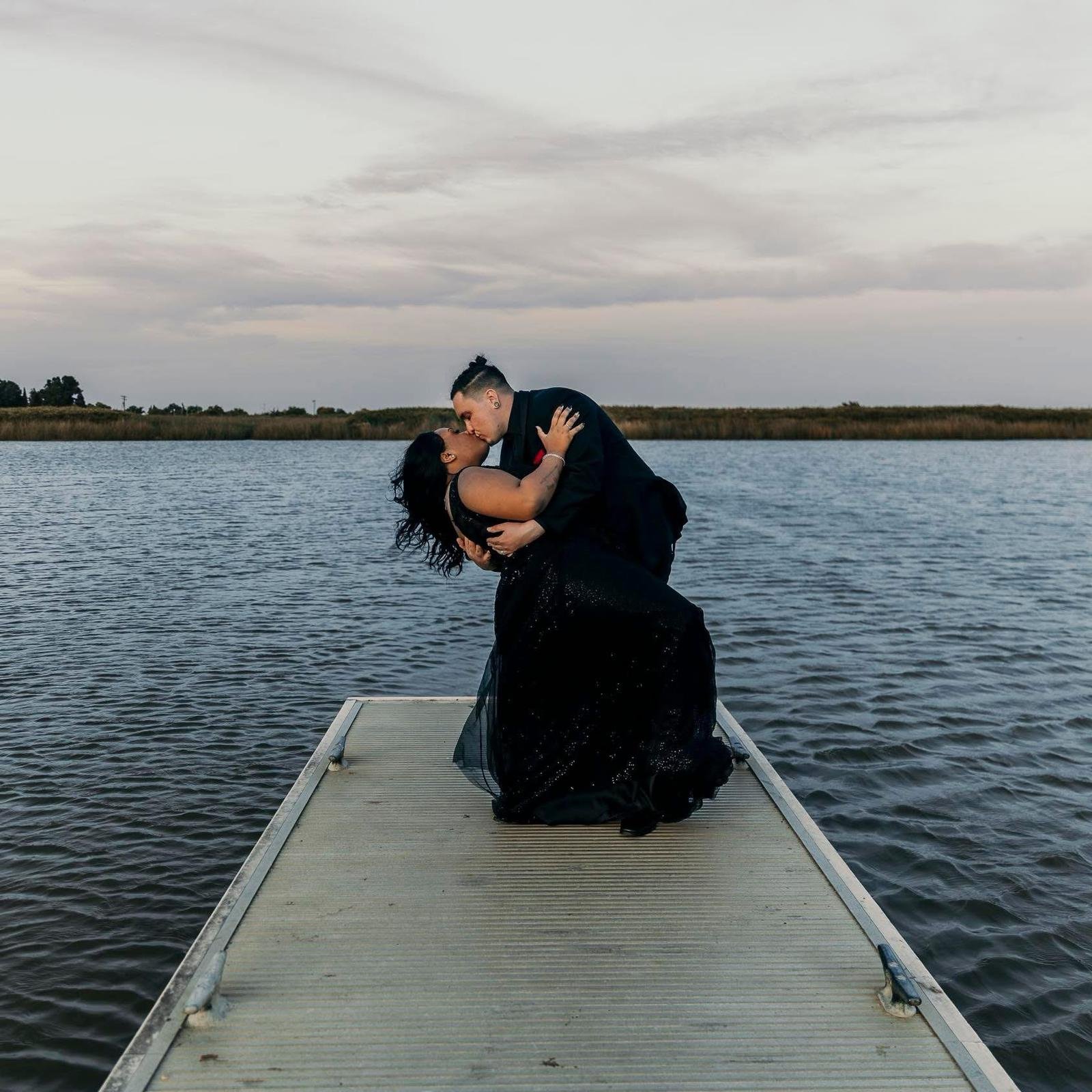 Des and Michael share a dip kiss on a dock at twilight