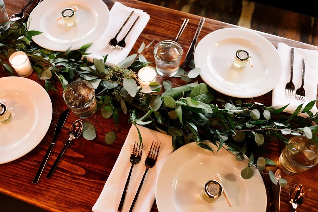 A reception table set with sage napkins, terracotta florals, and silver service