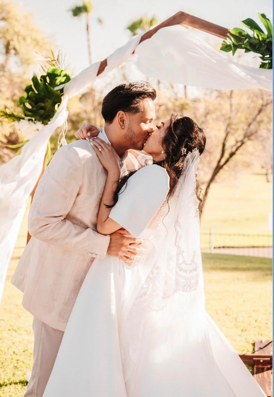 Erica and Yi share a kiss under a floral arch