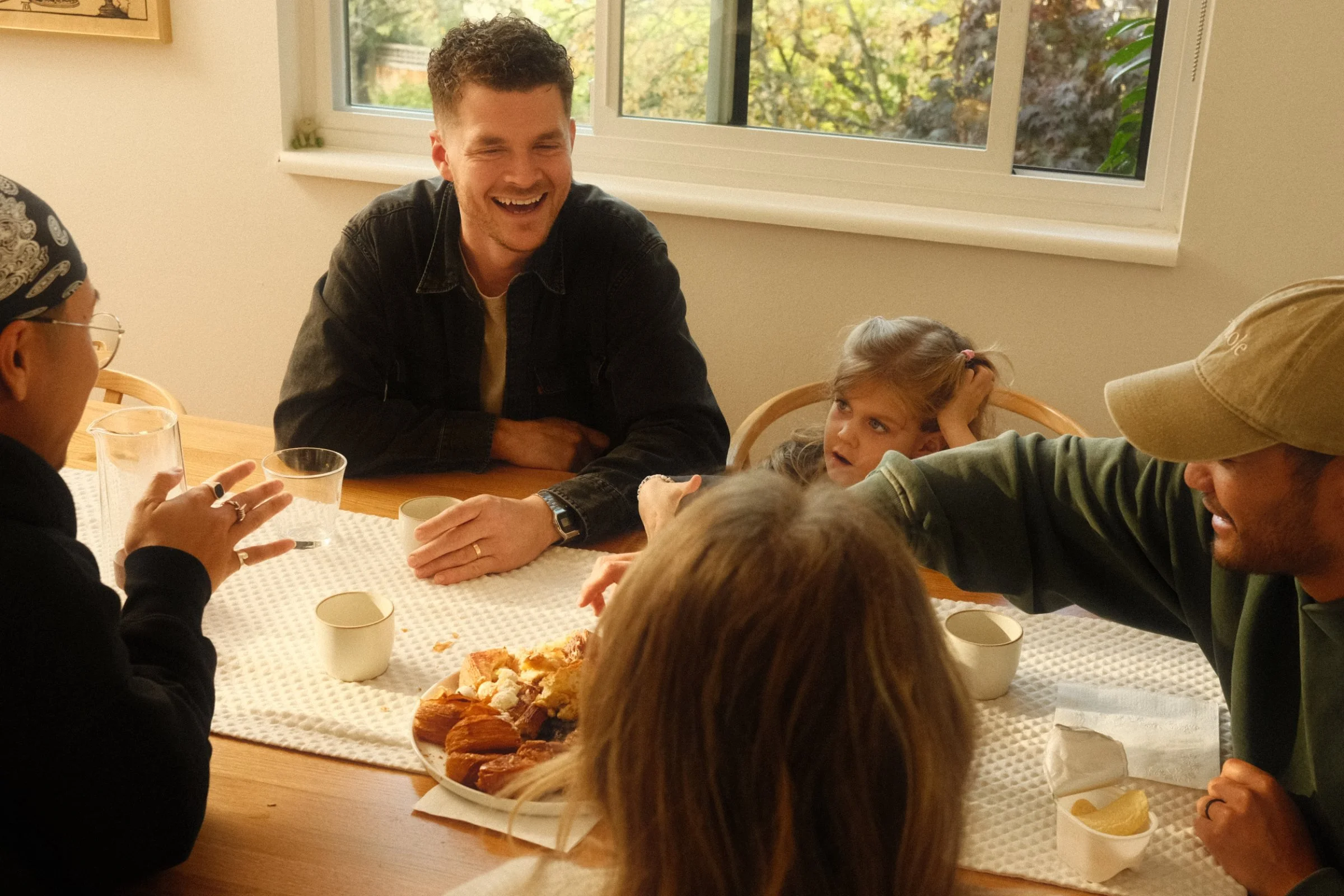 Friends and children laughing around a breakfast table