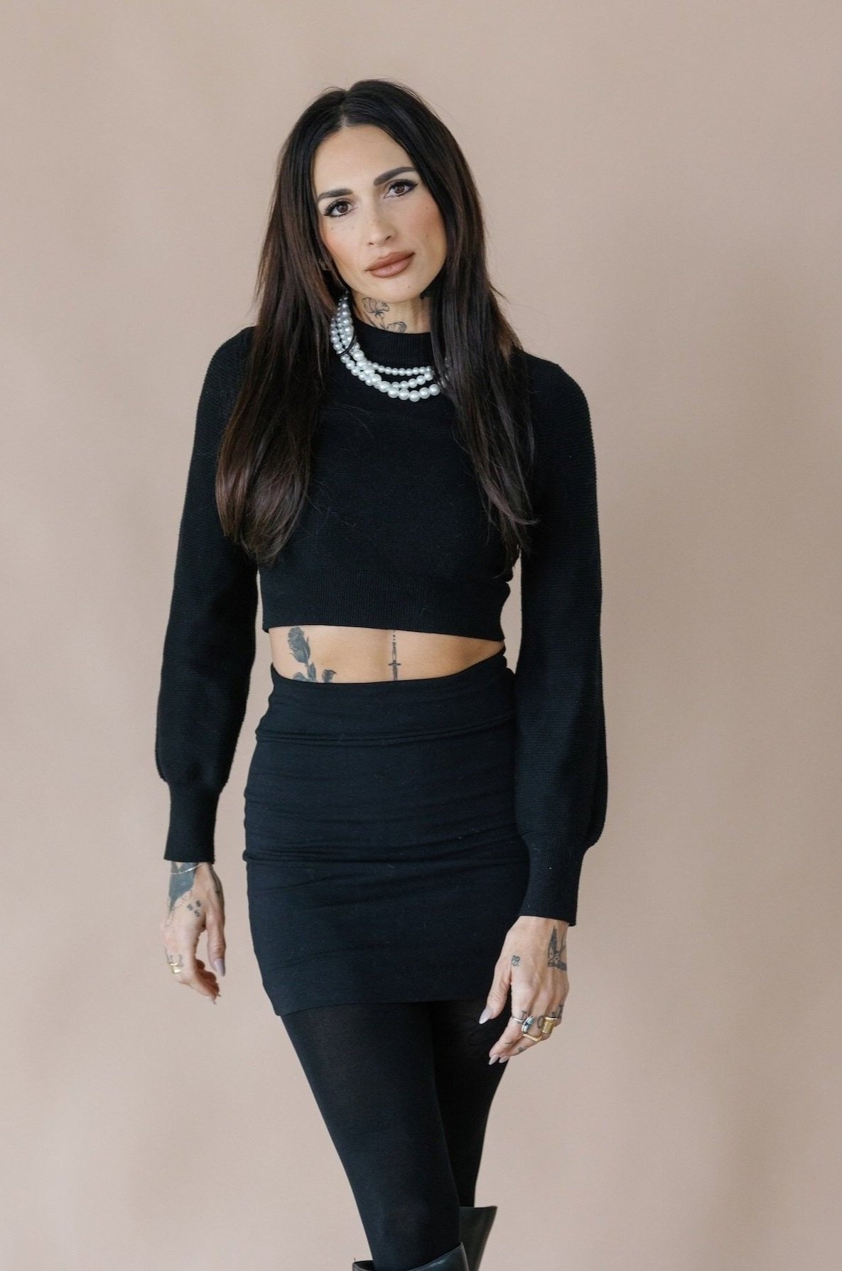 Romi in black, wearing layered pearls