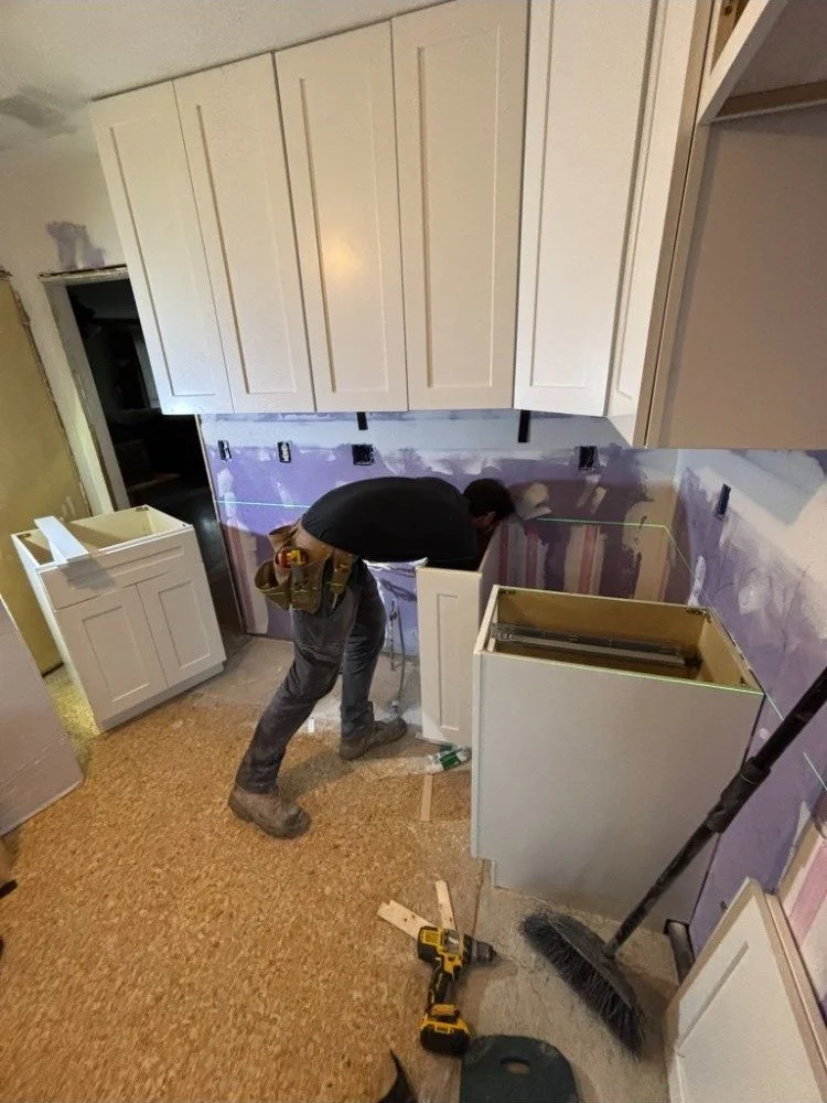 Craftsman installing white shaker upper cabinets in Delaware County PA kitchen remodel