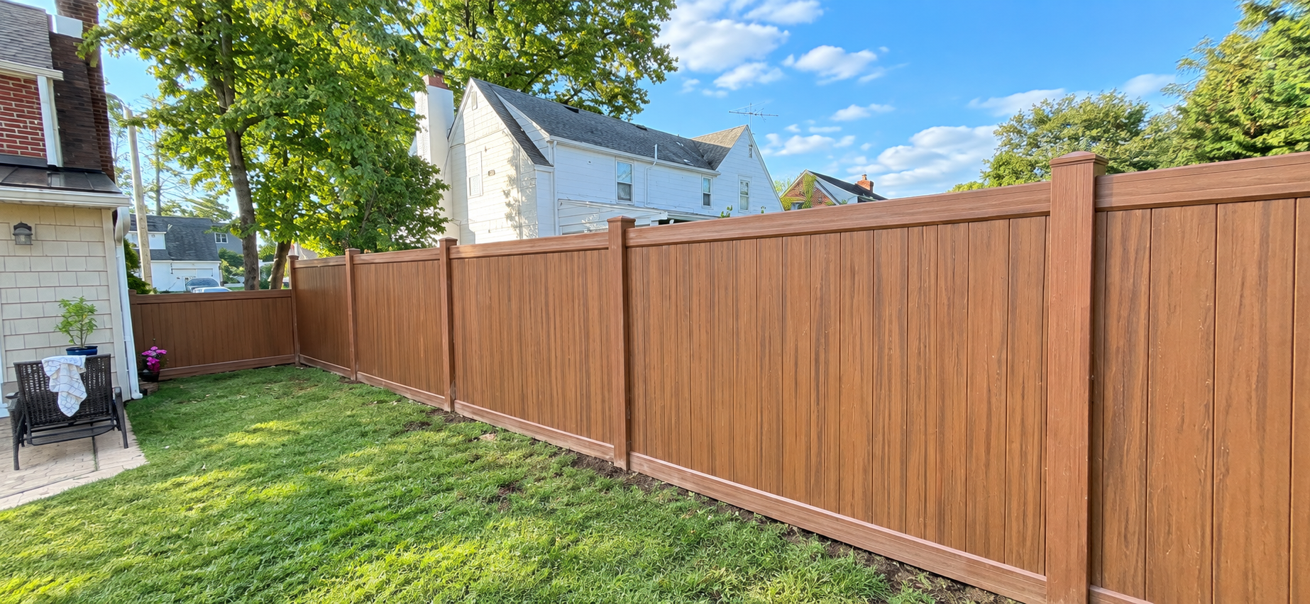 Long run of newly installed brown privacy fencing in a backyard