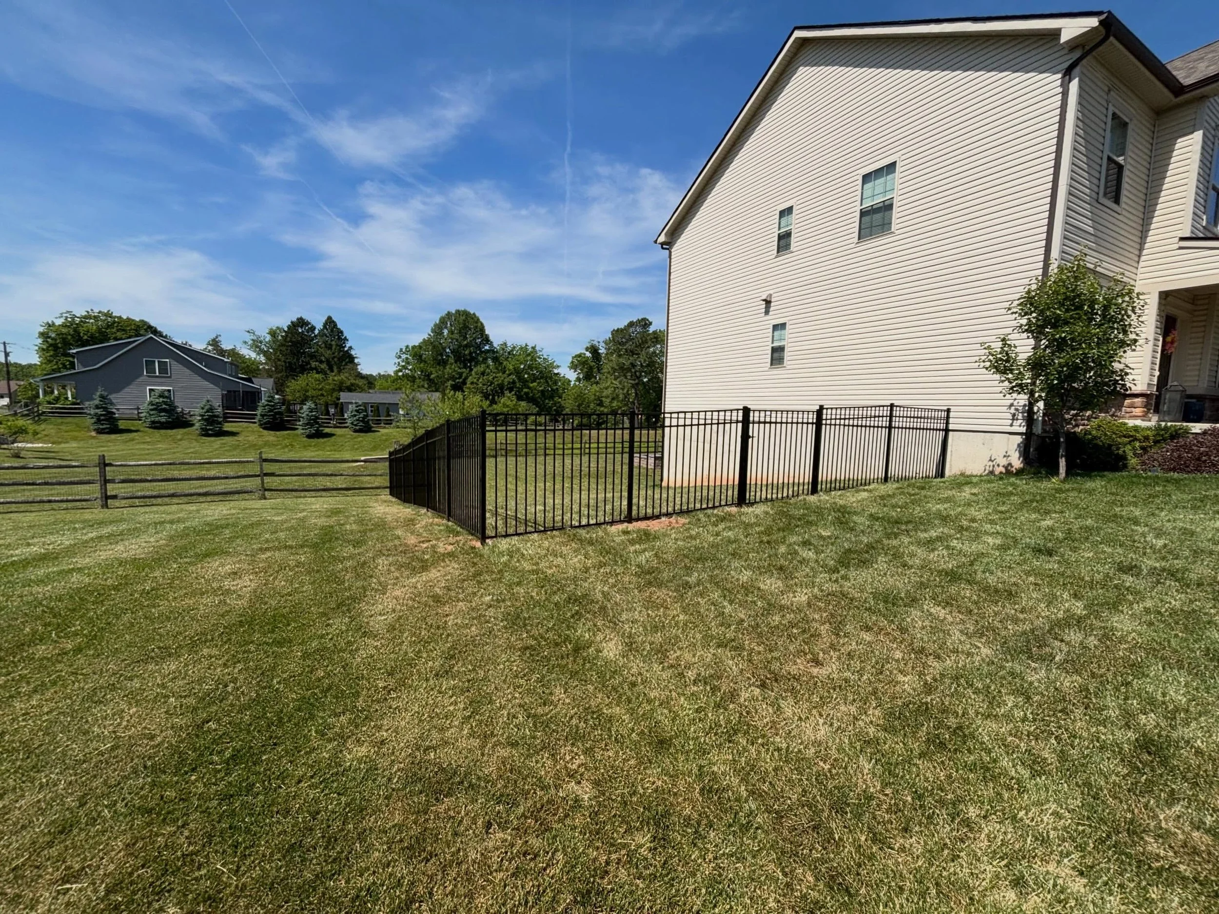 Black aluminum fence installed around a residential backyard