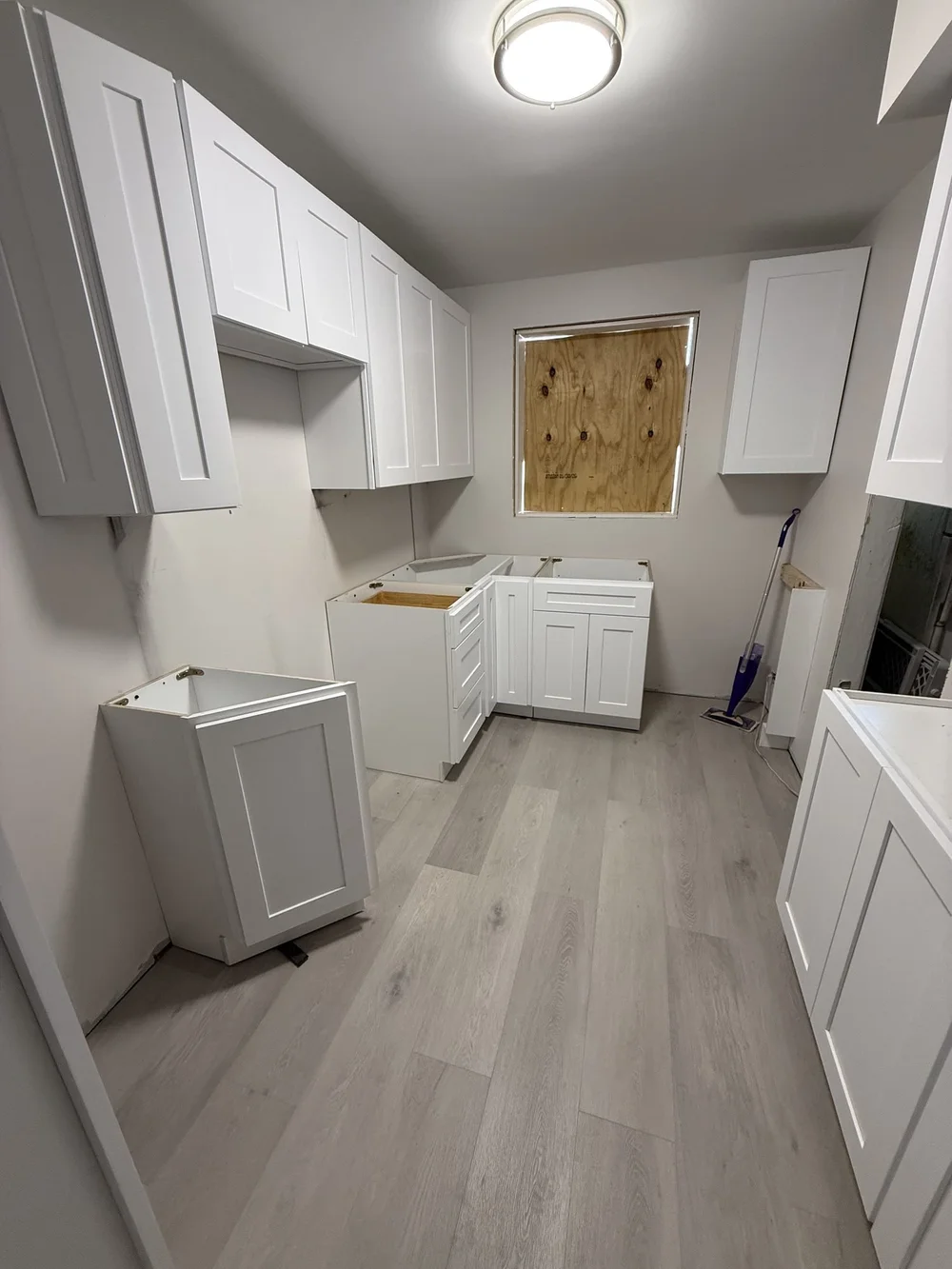 Kitchen remodel in progress with white shaker cabinets set before countertops