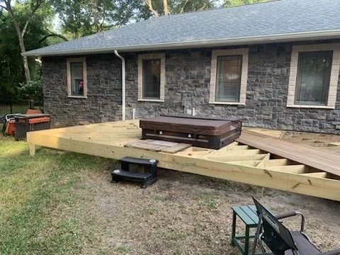 Deck construction beside a brick house