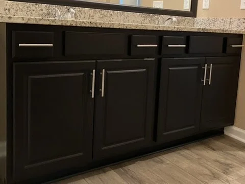After refinishing — Tricorn Black vanity cabinets with silver bar pulls