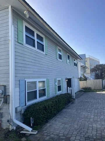 Before painting — weathered siding and green shutters along the driveway