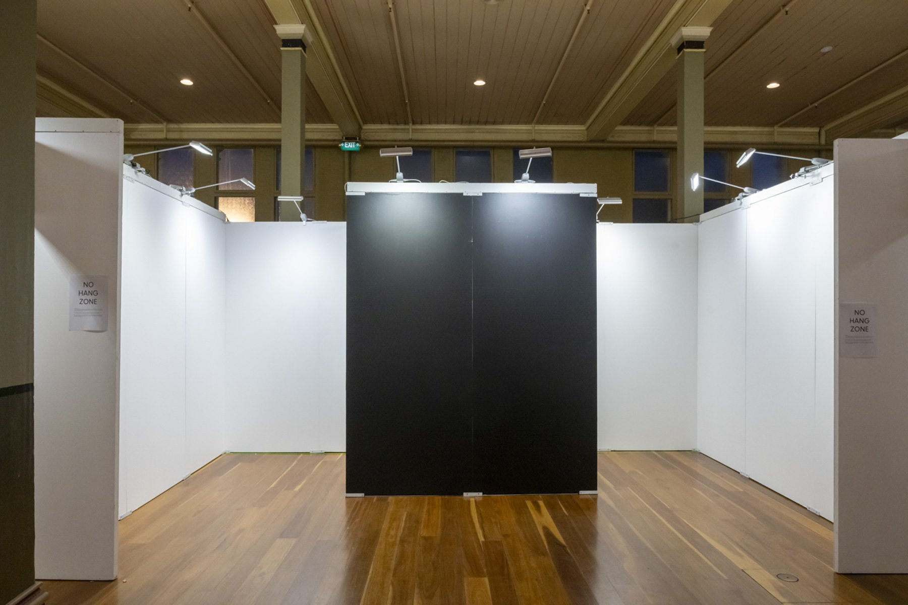 Bare white stand walls and a black feature wall inside the Royal Exhibition Building before the fair