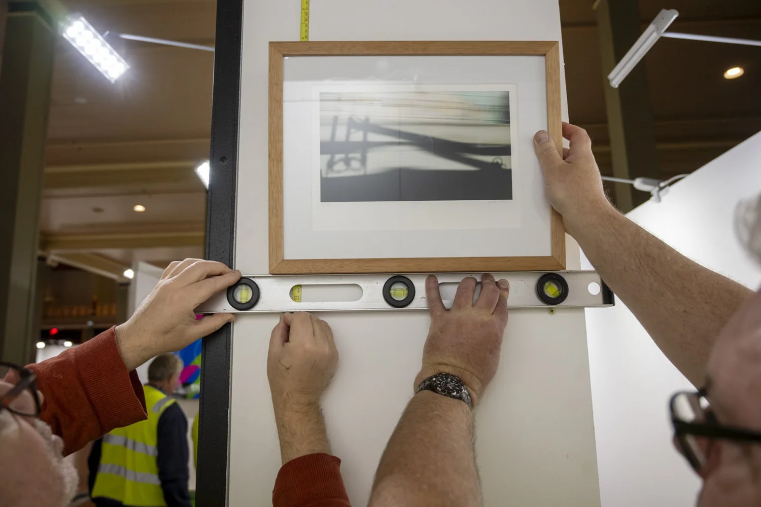 A spirit level held against a framed photograph during the hang