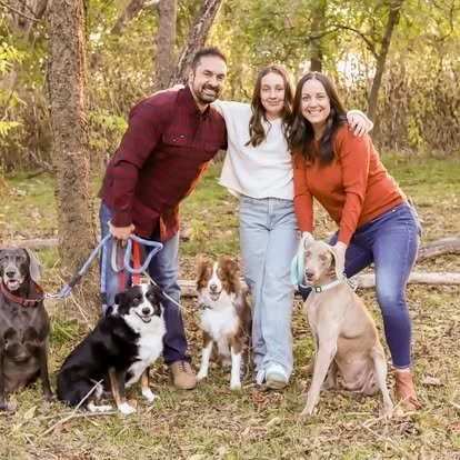 A family with their dogs, including two Weimaraners, in a wooded park