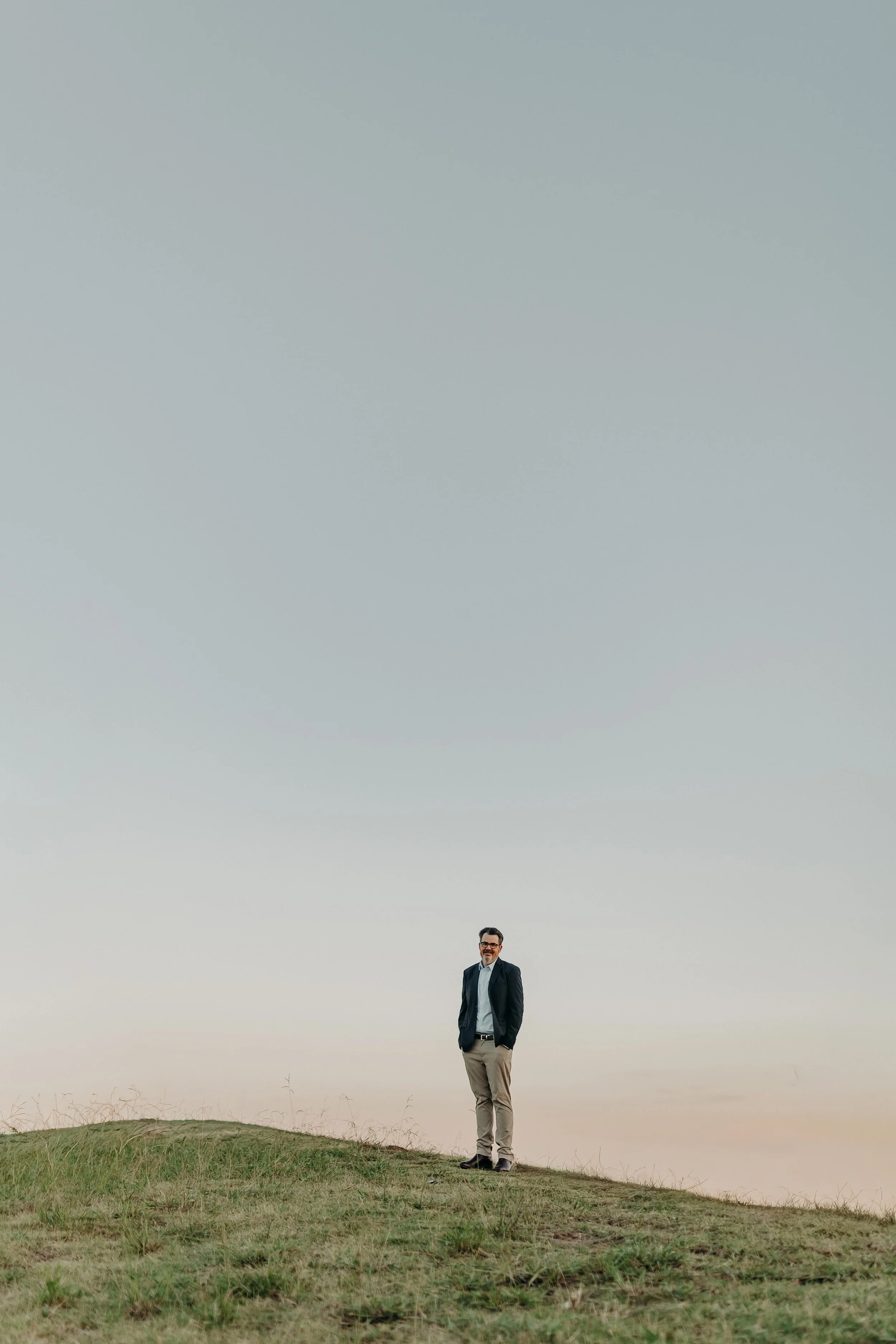 Jon Bowly, clinical nutritionist, standing on a grassy hilltop under a wide evening sky