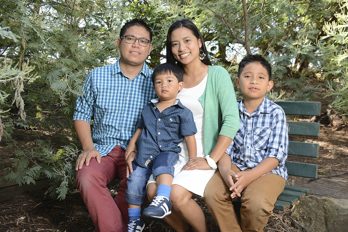 Family of four sitting together on a garden bench