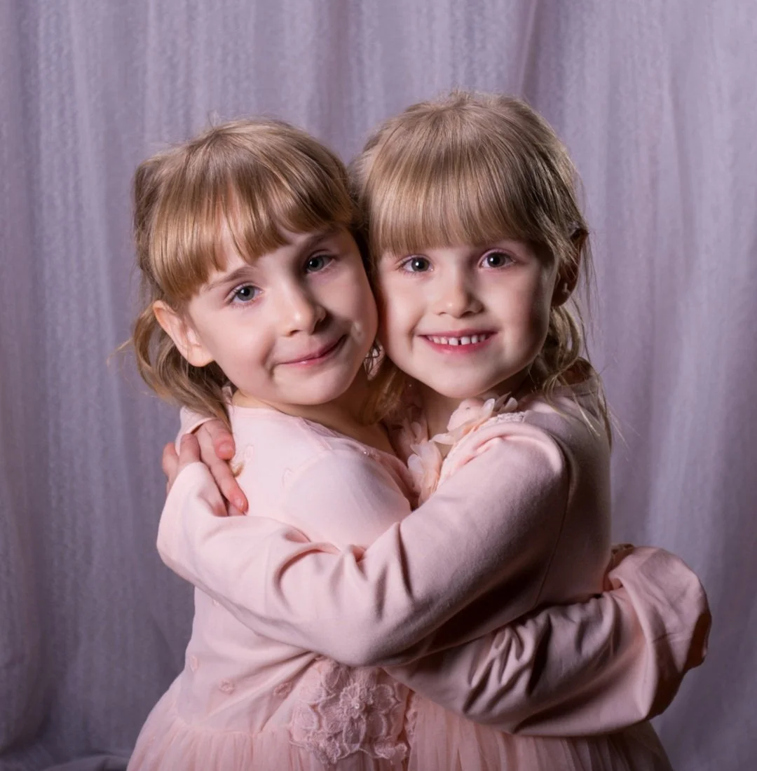Two children embracing and smiling in a portrait by David Pleydell