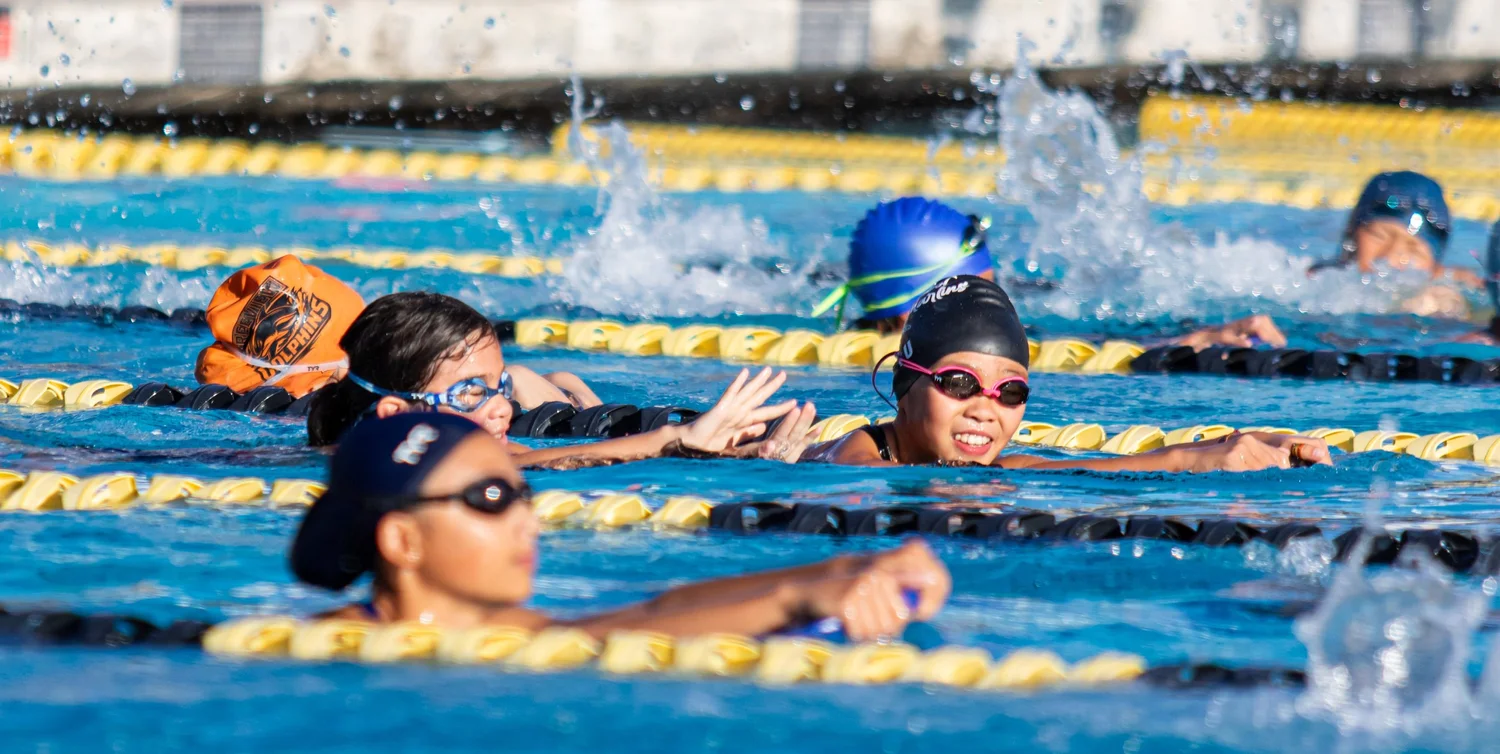 Young swimmers smiling at the lane line between sets at the Chabot College pool