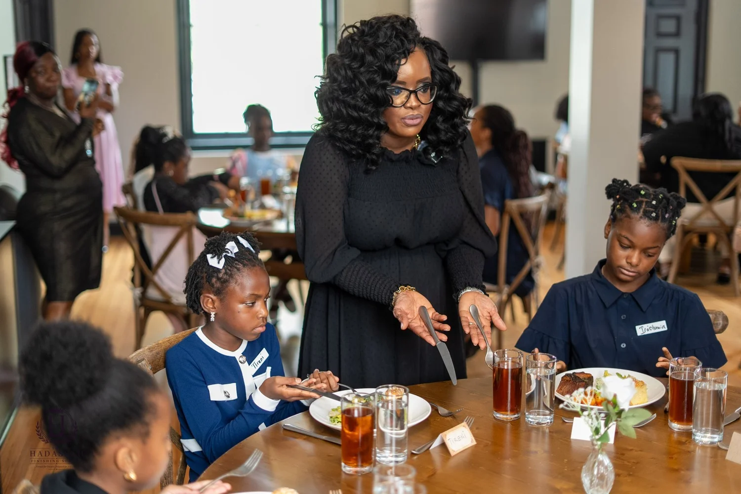 A mentor demonstrating table etiquette with participants seated around a table