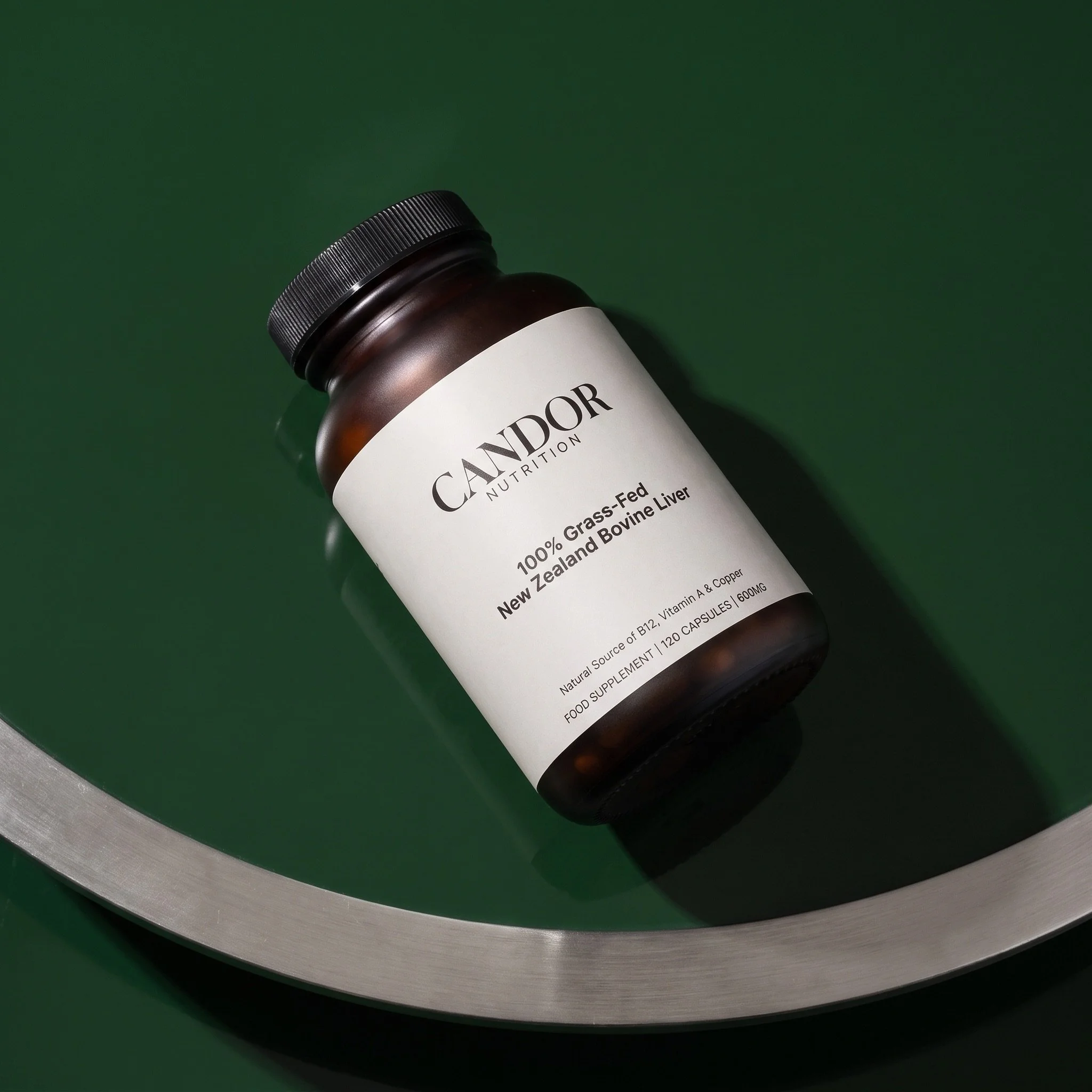 Candor Nutrition jar on a deep green surface beside a brushed metal arc