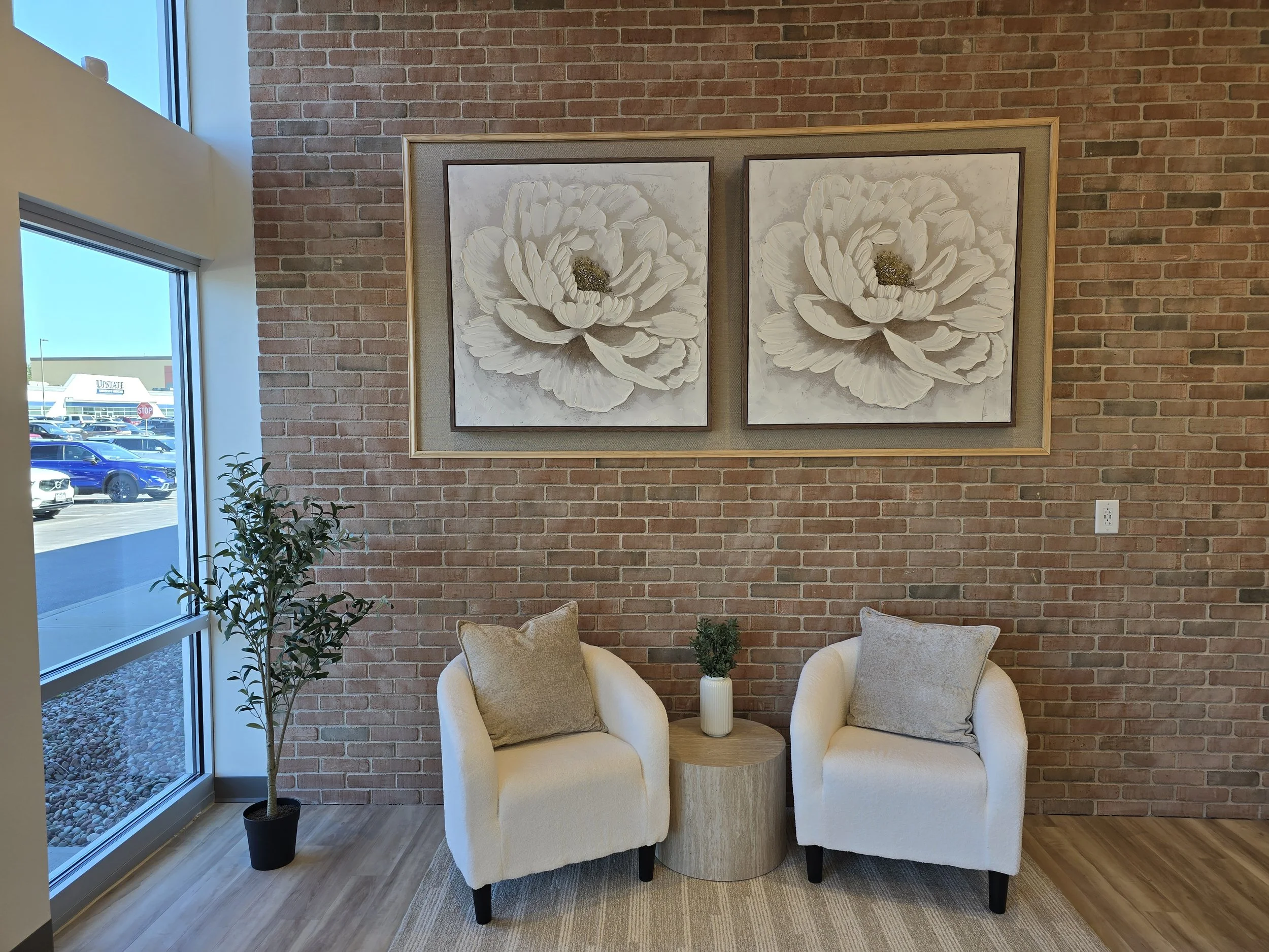 A quiet lounge with cream chairs and botanical artwork at SkanWell in Camillus